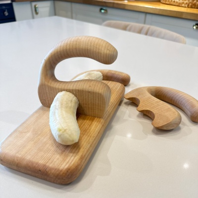 Wooden chopper and salad spatula on a cutting board with a banana