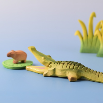 Crocodile playfully interacting with a small capybara on a lily pad