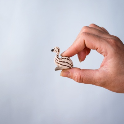 Sitting emu chick figure held gently between fingers
