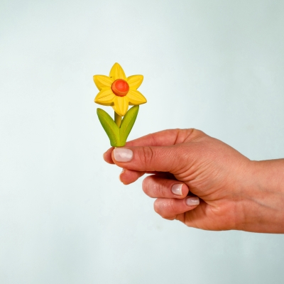 Hand holding a small yellow wooden toy daffodil showing its delicate craftsmanship and size