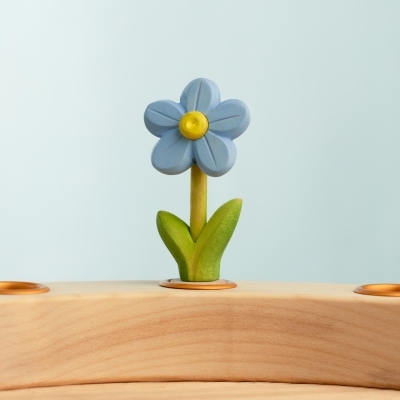 Hand-painted wooden toy forget-me-not flower resting in a wooden celebration ring