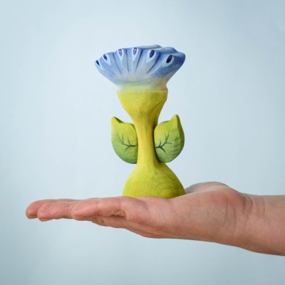Close-up of Spring Flower - Flama wooden toy with blue and purple petals, held in a hand, showcasing its eco-friendly, handcrafted design.