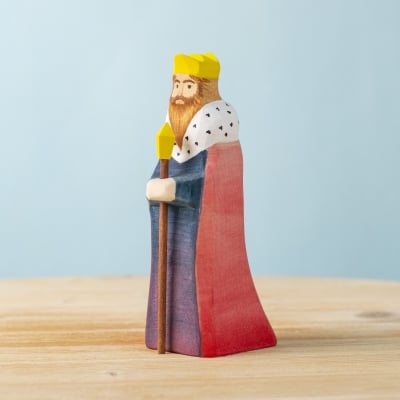 Wooden King figurine with red and blue robes, standing on a table.