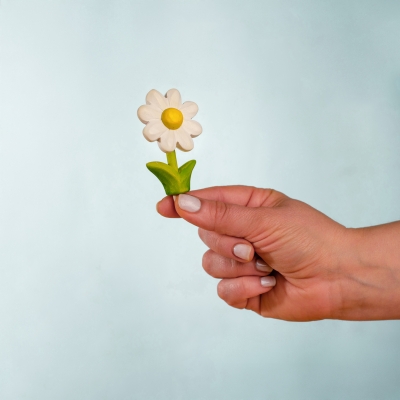 Woman holding a small Waldorf wooden daisy toy in her hand