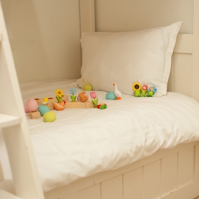 Handcrafted wooden sheep toys grazing near spring flowers and a pastel pink wooden Easter egg