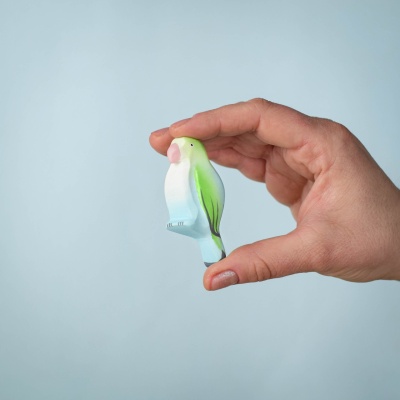 A hand holding the Blue Lovebird toy, showcasing its compact and safe design for children.