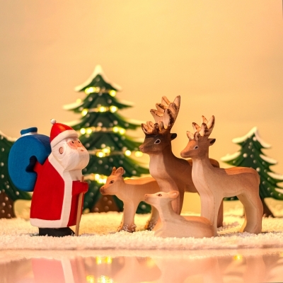 Sitting Reindeer Calf wooden figure placed next to a wooden Santa Claus and Standing Calf
