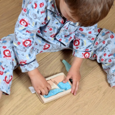 A toddler sitting on the floor, deeply engaged in solving the Dinosaur Puzzle.