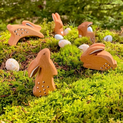Wooden rabbit toy nestled amongst leaves and acorns for an autumnal touch.