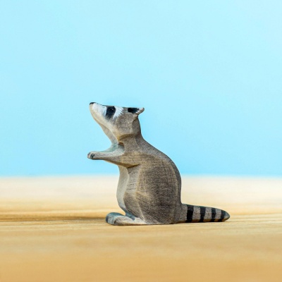 Wooden raccoon toy sitting upright, part of the raccoon family set by Bumbu Toys