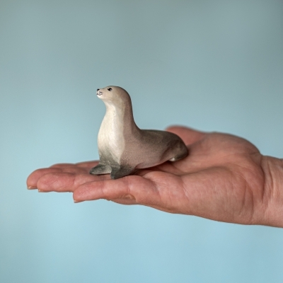 Hand holding the curious wooden seal toy to show the medium size in the set.