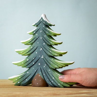 Handcrafted Large Wooden Snowy Fir Tree held in hand for scale.