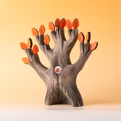 Autumn tree toy with orange leaves on warm background.