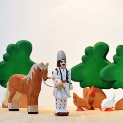 Peasant toy placed in a miniature wooden barn with other farm animals.