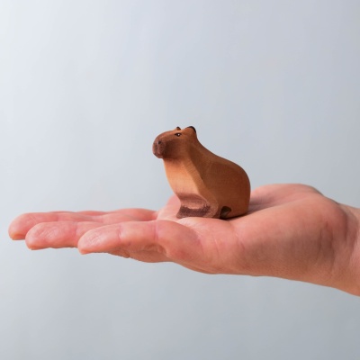 Small wooden capybara sitting in a hand, showing its size.