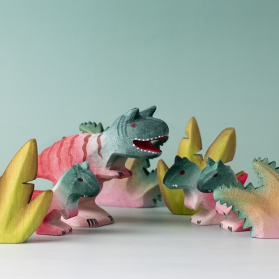 Carnotaurus duo in a prehistoric play scene with other dinosaurs and foliage.