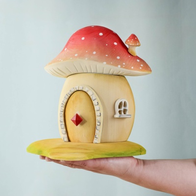 A child holding the Toadstool House, showcasing its size and craftsmanship.