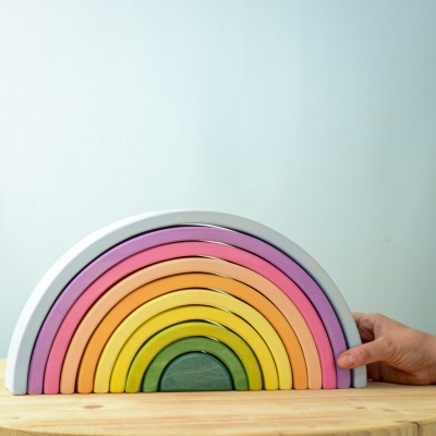 Large Rainbow wooden toy being adjusted by a hand.