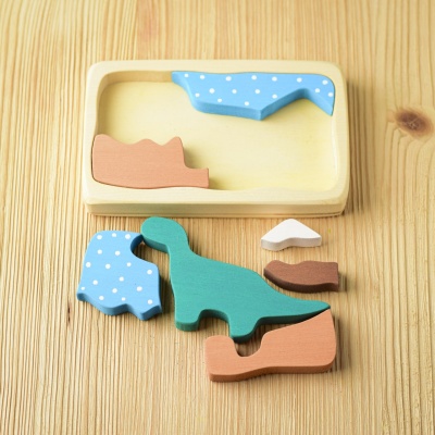 Individual wooden dinosaur puzzle pieces scattered playfully on a table.