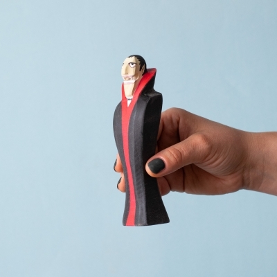 Wooden Dracula toy held in a hand to show scale and painted detail