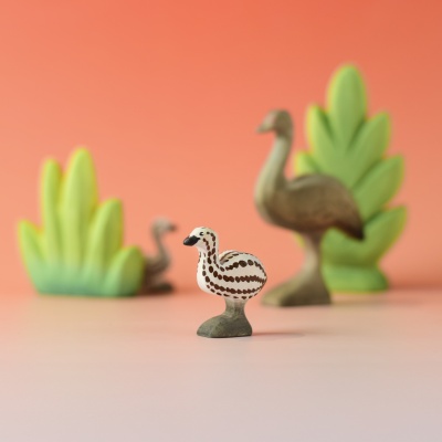 Emu chick figure in front of greenery and emu family play scene