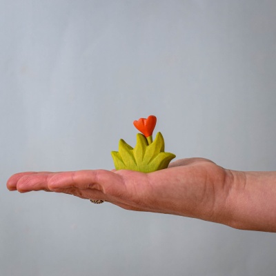 A small wooden flower in the palm of a hand, showcasing its delicate design.