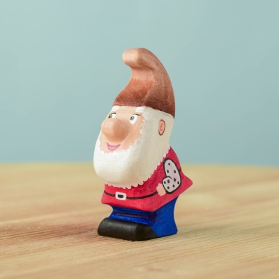 Handcrafted wooden Whittle Dwarf with a red tunic and playful expression.