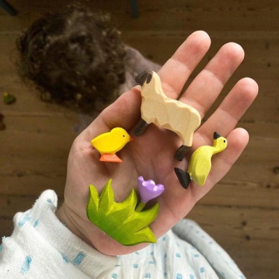 Child holding a BumbuToys Wooden Chick up to the light, admiring its simple form.