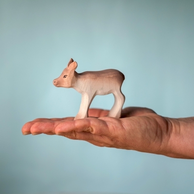 Small wooden Reindeer Calf toy held in an adult hand to show scale and smooth natural wood finish.