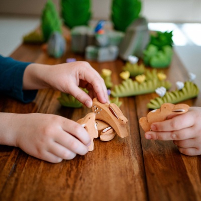 Wooden rabbit toy paused next to a small dollhouse.
