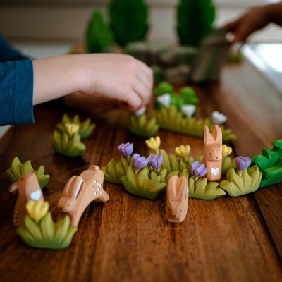 Child's hand gently petting the wooden rabbit toy.