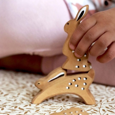 Side profile of wooden rabbit toy, highlighting its leaping shape.