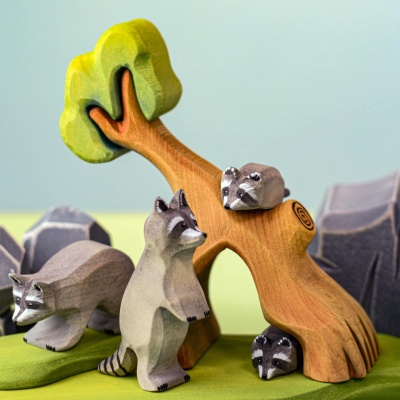 Wooden raccoon standing by a miniature tree