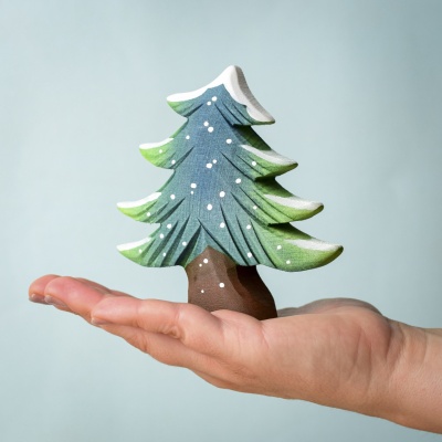 Handcrafted Small Wooden Snowy Fir Tree held in hand for scale.