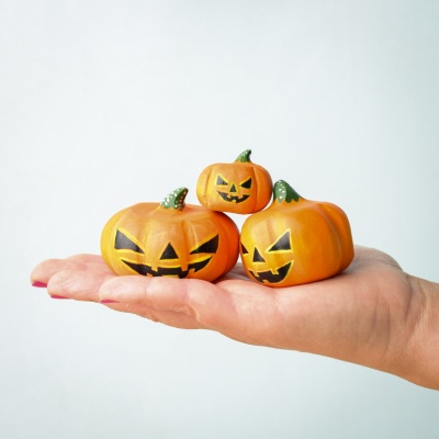 Three handcrafted wooden Halloween pumpkins in a hand.
