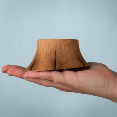 A Tree Stump wooden toy shown on a hand, showcasing its compact size and smooth finish.