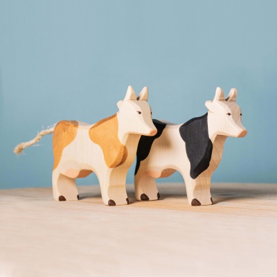 Close-up photo showcasing the smooth wood grain, hand-painted details, and black and white spots of the White and Black Cow.