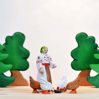A child using the BumbuToys White Hen to create a pretend egg-laying scene.