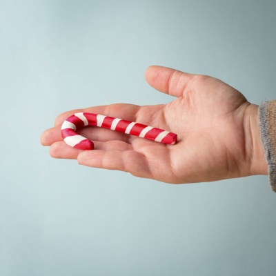 Handcrafted Wooden Candy Cane held in an adult hand to illustrate its size and craftsmanship.