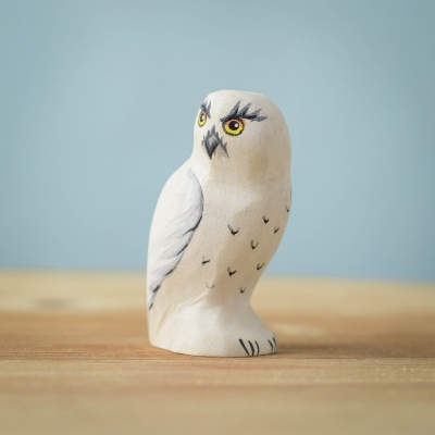 Handcrafted wooden Snowy Owl toy with detailed snowy plumage, standing on a table.