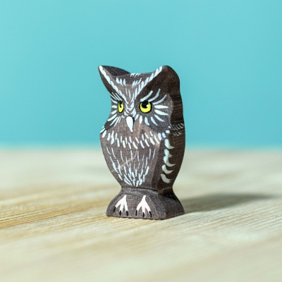 Image of the wooden owl toy standing on a windowsill, sunlight streaming through its large eyes.