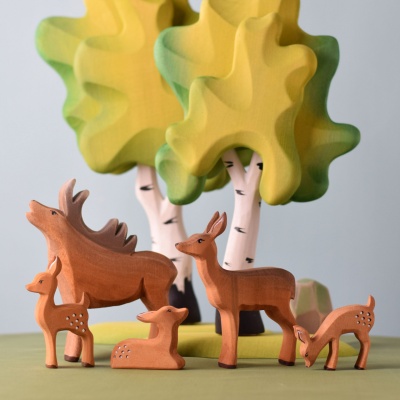 The wooden stag toy incorporated into a nature-themed play scene with wooden trees and rocks.