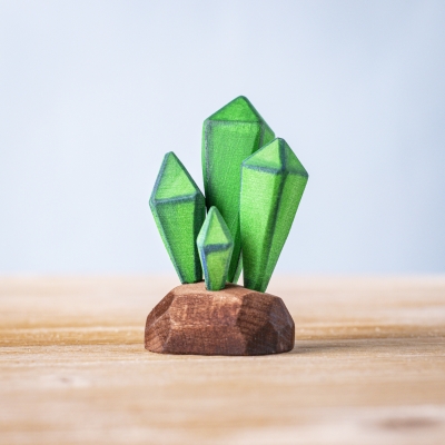 Wooden green crystals with faceted tips standing on a brown base.