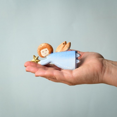 Close-up of wooden Christmas Angel in hand showing detail.