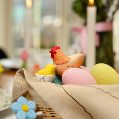 Close up of a painted wooden hen and hatching chick toy in a spring basket setting