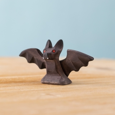 Handmade wooden Flappy Bat toy with open wings on wooden surface.