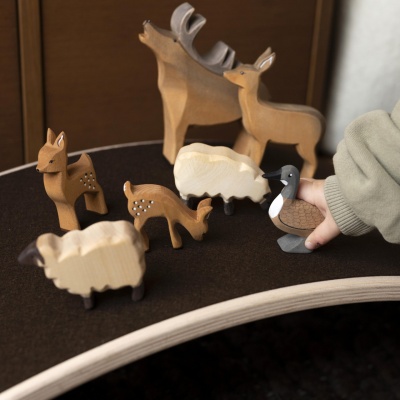 The Wild Goose 'flying' across a miniature nature scene with other wooden animal figures like trees and rabbits.