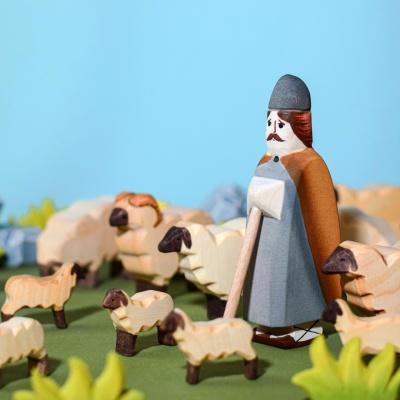 The lamb figurine grazing on miniature wooden flowers or leaves.