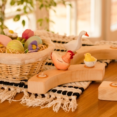 Festive spring table setting featuring lit candles in a wooden ring and a basket of pastel eggs