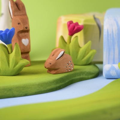 Wooden baby rabbit toy placed in a forest-themed play scene